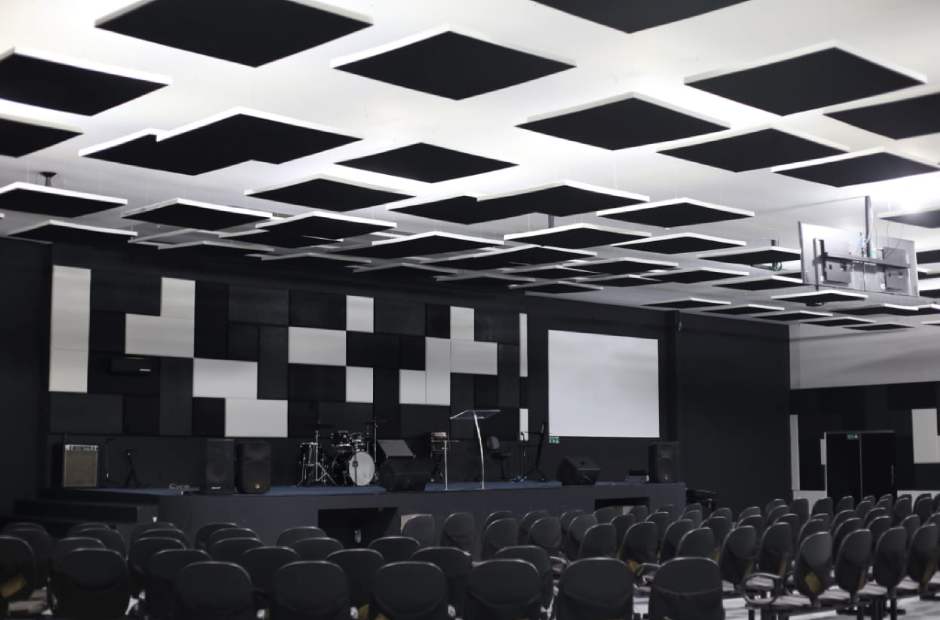 an auditorium with absorbent panels on the ceiling and walls for better sound insulation.
